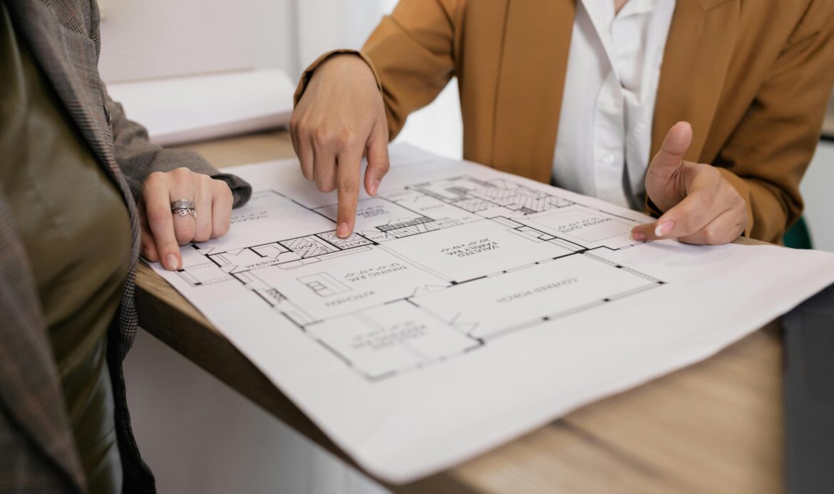 Two professionals reviewing architectural plans, focused on floor layout and design details.